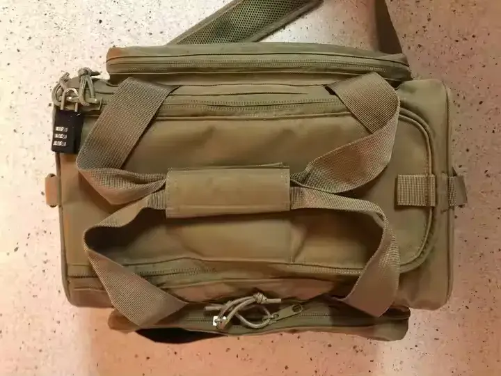 Top view of a closed tan tactical range bag with shoulder strap, dual handles, and visible lock on the zipper.