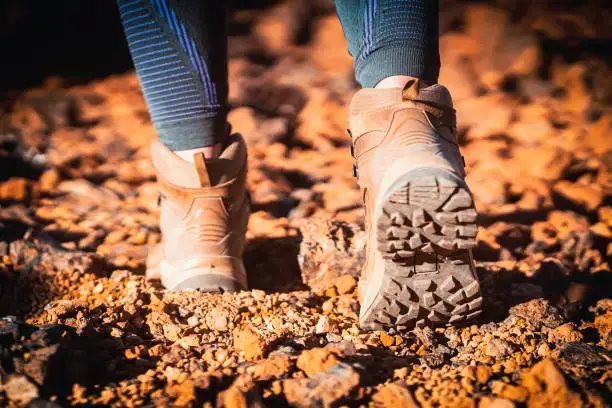 Legs in high hiking boots of coyote color with a textured sole close-up, tactical footwear