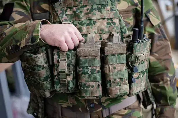Close-up view of military radio pouches and equipment attachments on a camouflage tactical vest