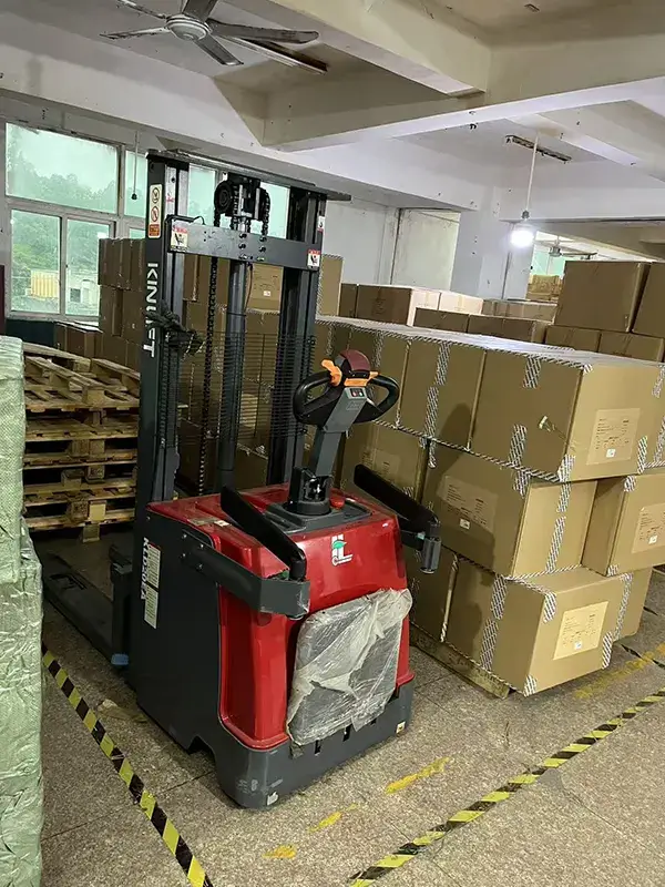Red forklift moving stacked cardboard boxes in our warehouse
